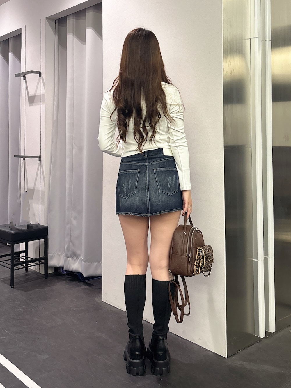 ホワイト系のTシャツ/カットソー、ブルー系のデニムスカート、ブラック系のバックパック/リュックを着用したレディースの秋コーディネートの3枚目の写真