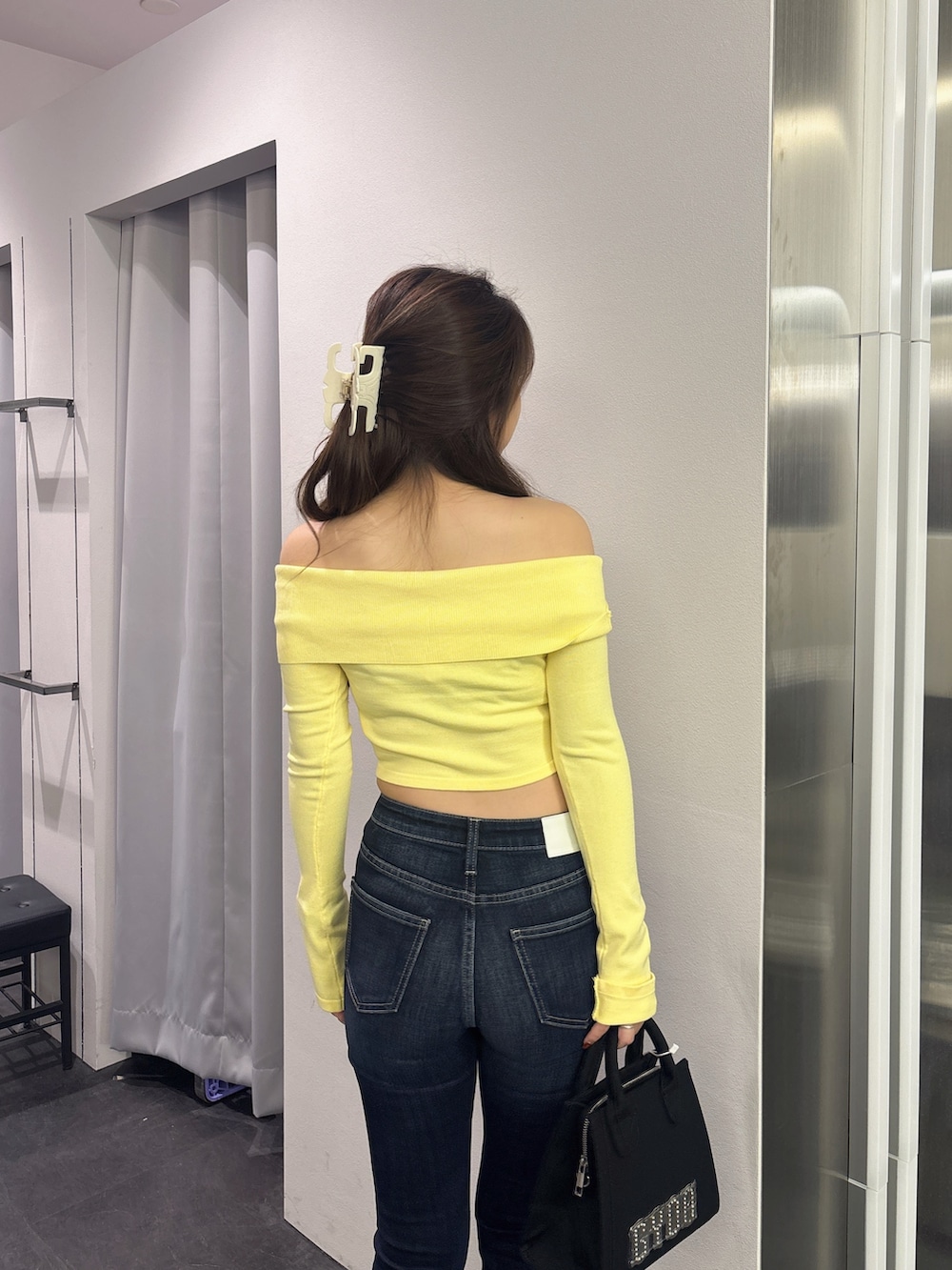 イエロー系のニット/セーター、ブラック系のハンドバッグ、ブルー系のデニムパンツを着用したレディースの秋コーディネートの6枚目の写真