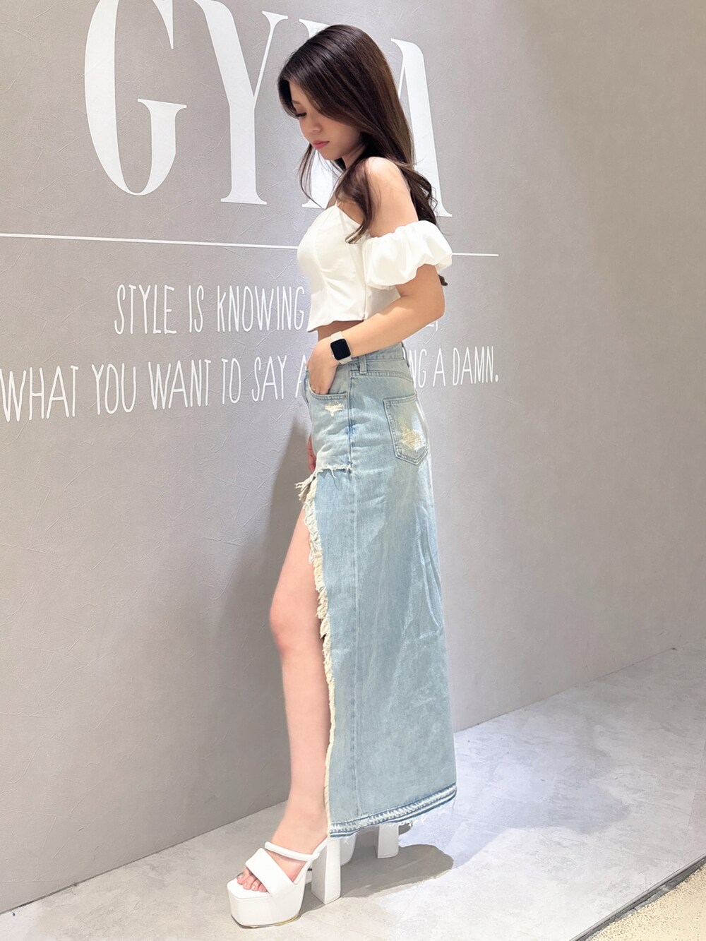 ホワイト系のシャツ/ブラウス、ブルー系のデニムスカート、ブラック系のサンダルを着用したレディースの春コーディネートの2枚目の写真