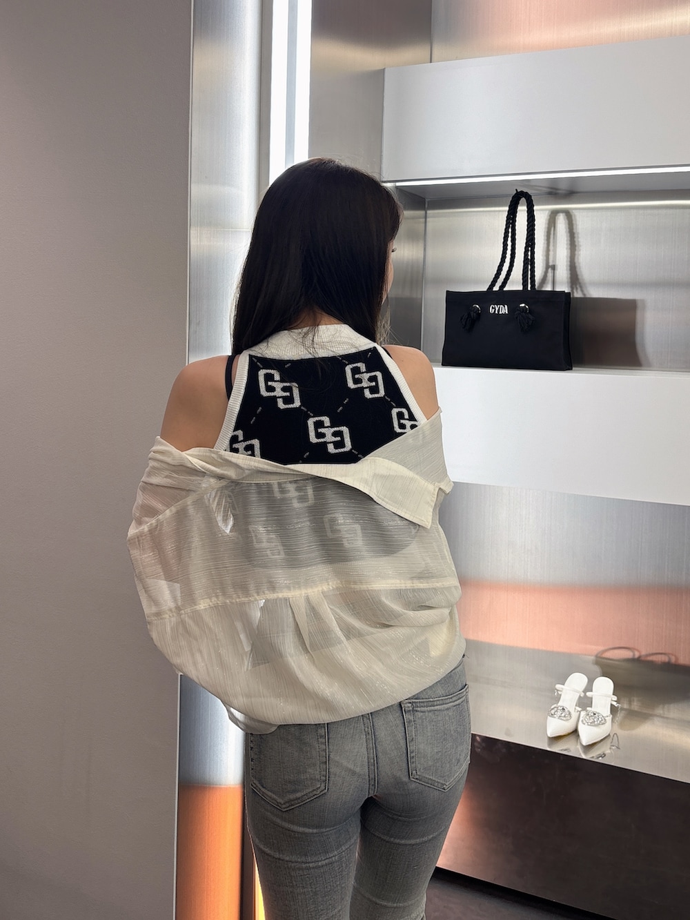 ブルー系のデニムパンツ、ブラック系のサンダル、ブラック系のタンクトップを着用したレディースの春コーディネートの6枚目の写真