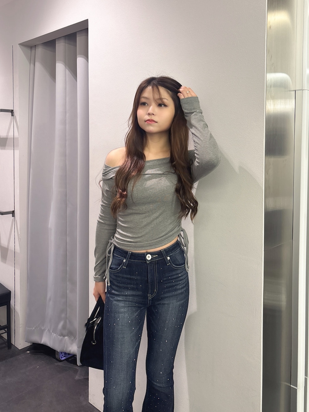 グレー系のTシャツ/カットソー、ブルー系のデニムパンツ、ブラック系のハンドバッグを着用したレディースの秋コーディネートの4枚目の写真