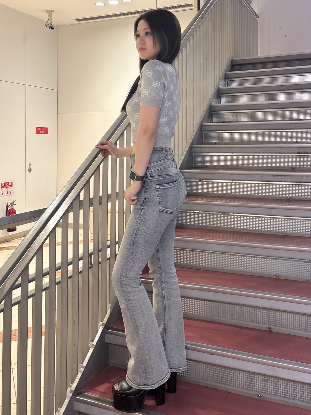 グレー系のニット/セーター、ブルー系のデニムパンツ、ブラック系のサンダルを着用したレディースの春コーディネートの2枚目の写真