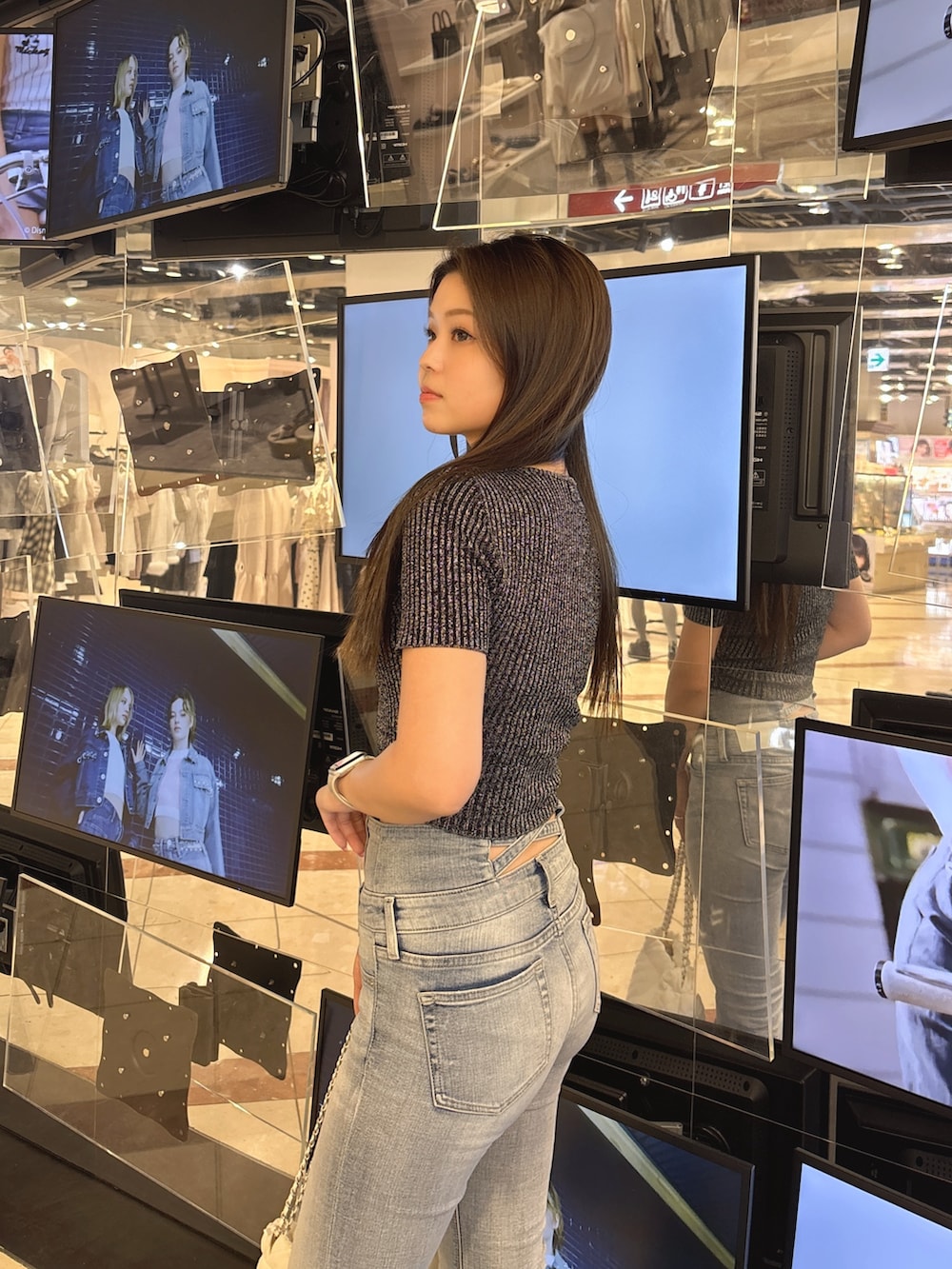 ブラック系のニット/セーター、ブルー系のデニムパンツ、ブラック系のブーツを着用したレディースの春コーディネートの5枚目の写真