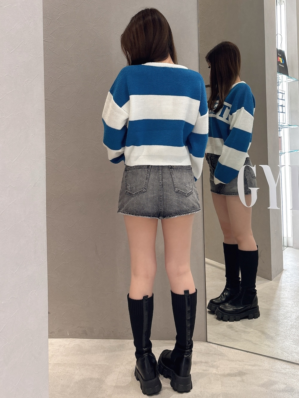 ブルー系のニット/セーター、ブルー系のデニムスカート、ブラック系のブーツを着用したレディースの秋コーディネートの3枚目の写真