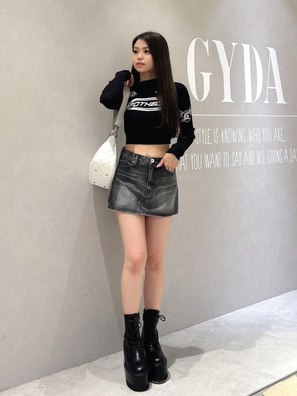 ブラック系のニット/セーター、ブラック系のデニムスカート、ブラック系のブーツを着用したレディースの秋コーディネートの2枚目の写真