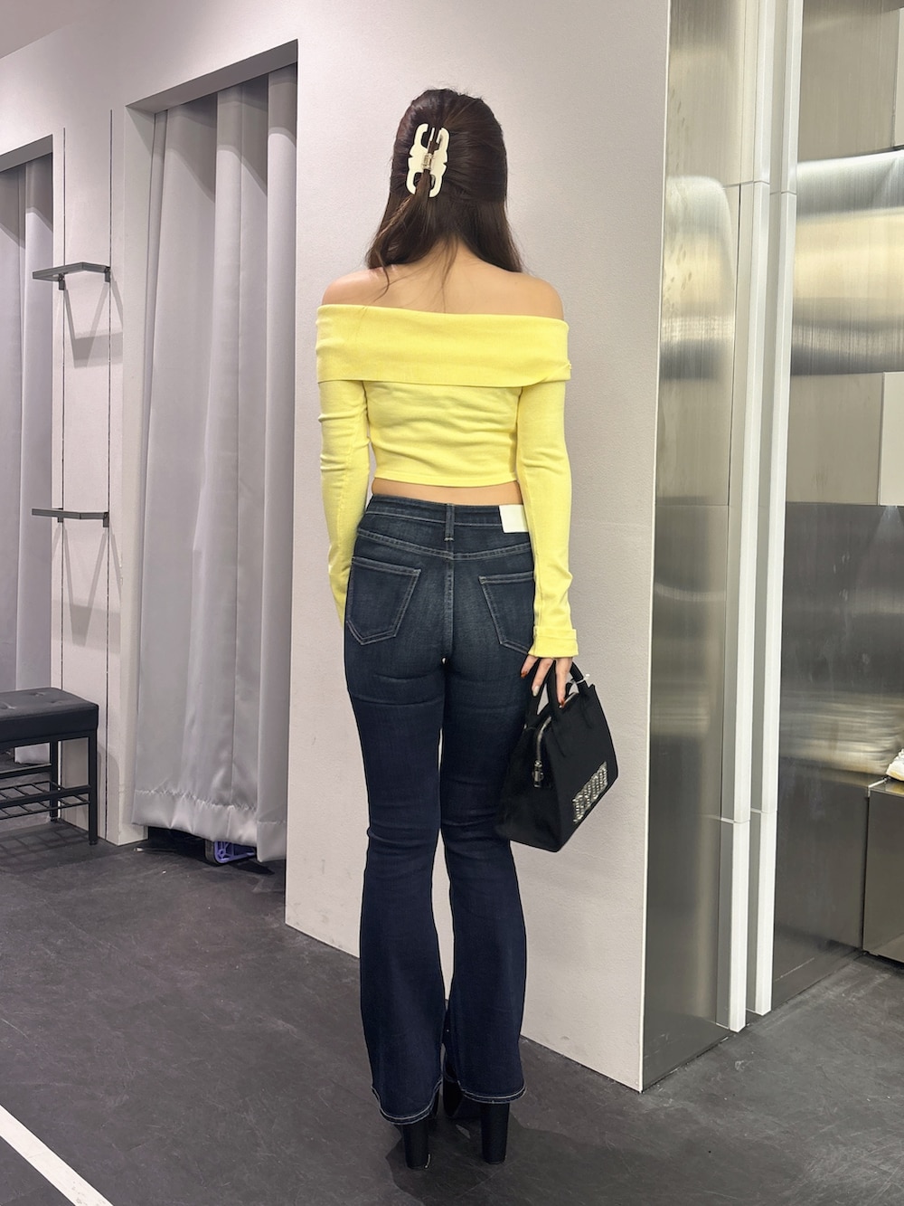 イエロー系のニット/セーター、ブラック系のハンドバッグ、ブルー系のデニムパンツを着用したレディースの秋コーディネートの3枚目の写真