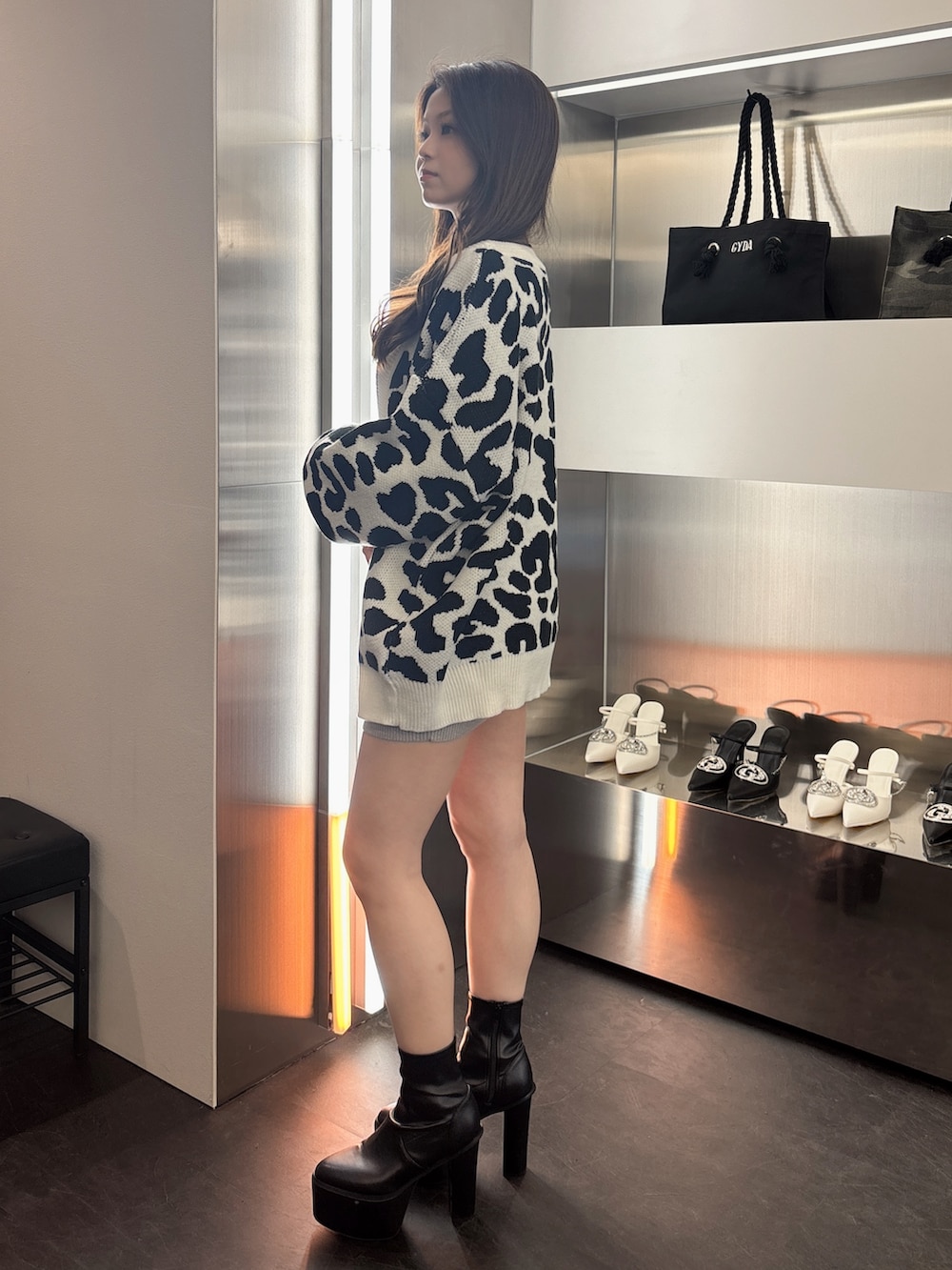 ブラック系のブーツ、ホワイト系のカーディガン/ボレロ、シルバー系のワンピースを着用したレディースの春コーディネートの2枚目の写真