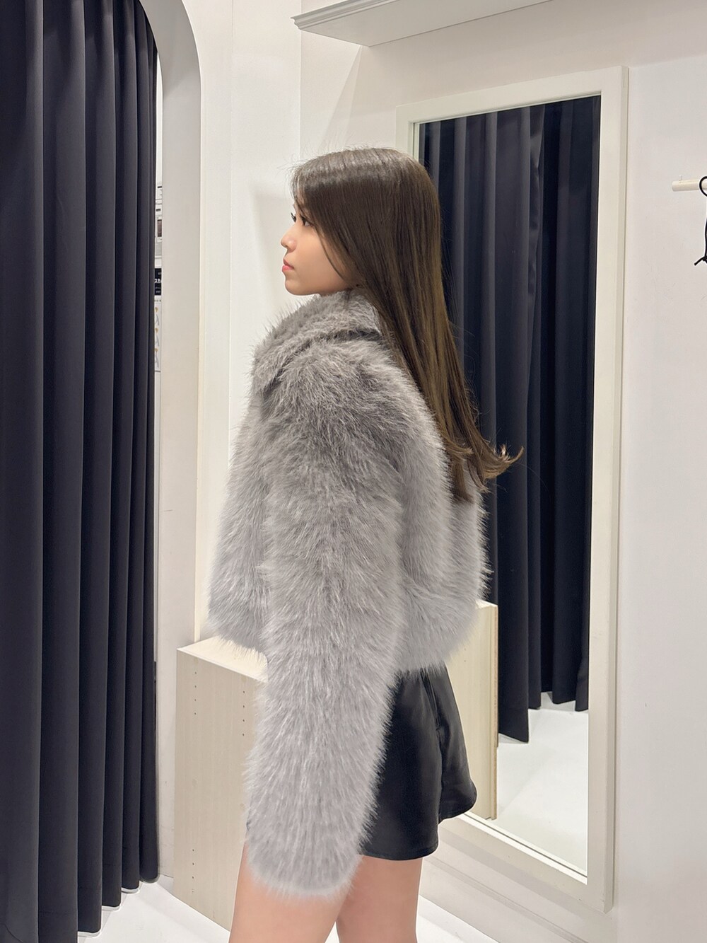 グレー系のダウンジャケット/コート、ブラック系のスカート、ブラック系のブーツを着用したレディースの秋コーディネートの6枚目の写真