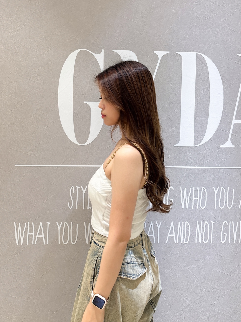 ホワイト系のキャミソール、ブラック系のサンダル、ブルー系のデニムパンツを着用したレディースの夏コーディネートの5枚目の写真