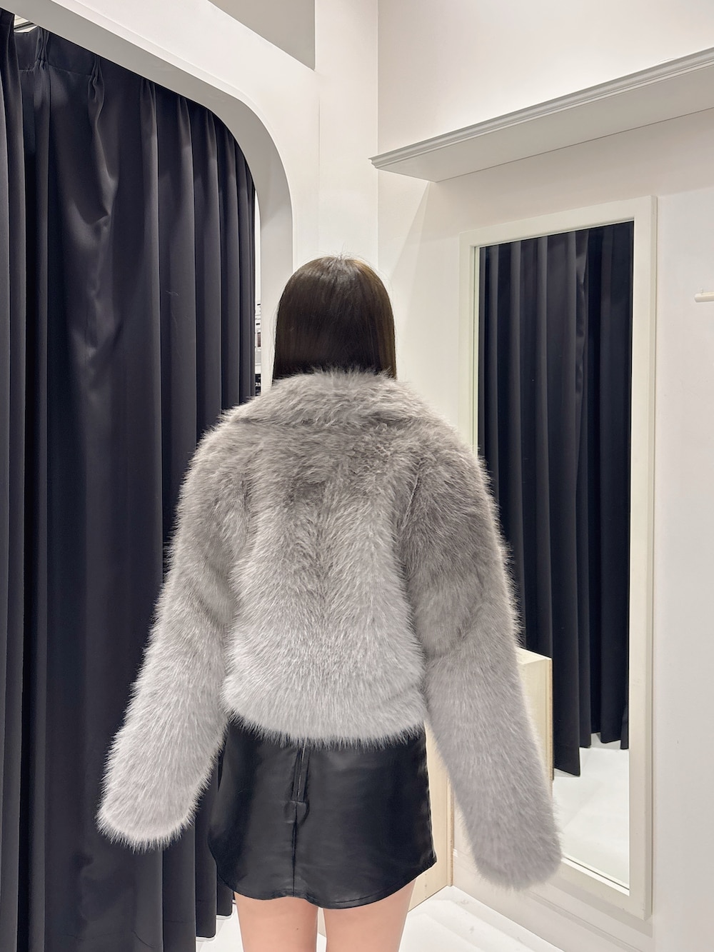 グレー系のダウンジャケット/コート、ブラック系のスカート、ブラック系のブーツを着用したレディースの秋コーディネートの7枚目の写真