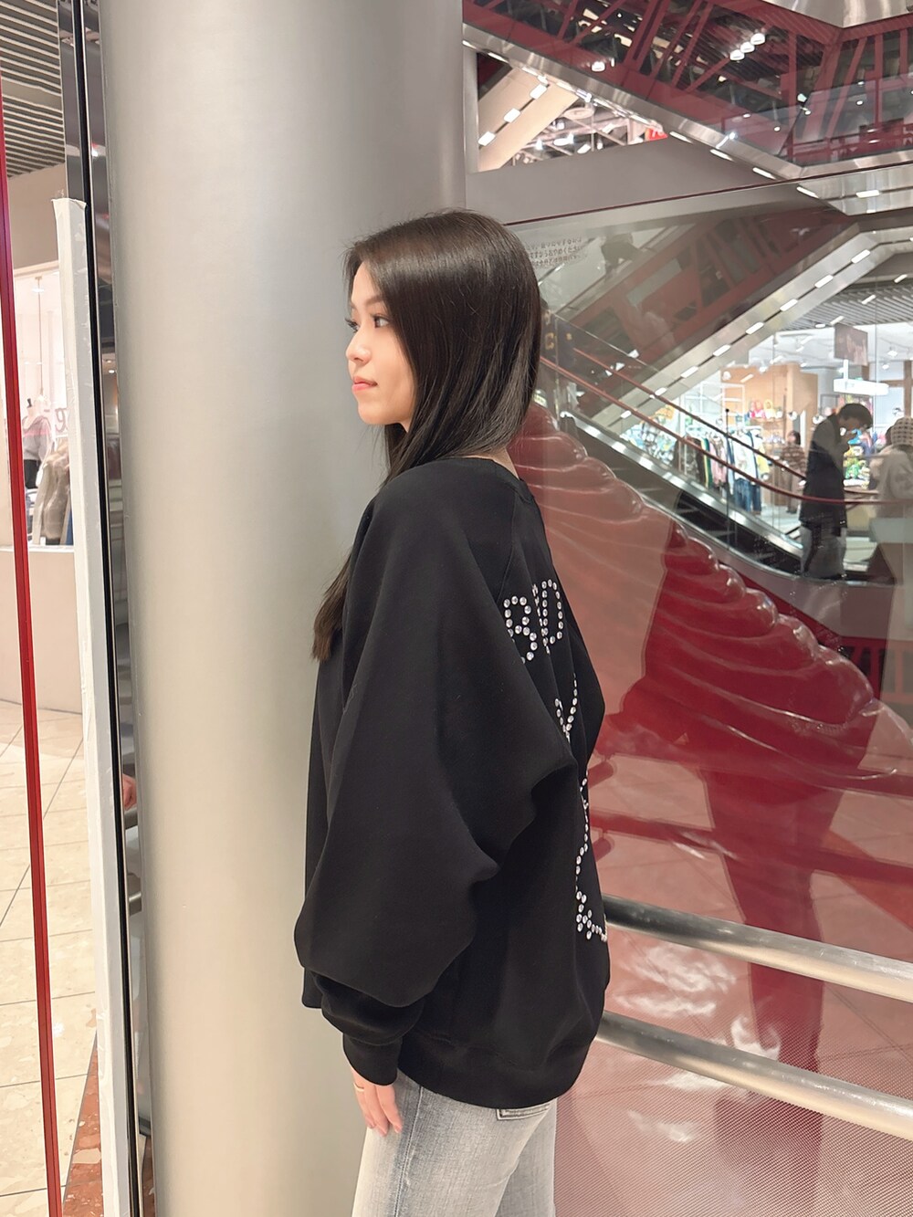 ブラック系のスウェット、ブルー系のデニムパンツ、ブラック系のブーツを着用したレディースの冬コーディネートの5枚目の写真