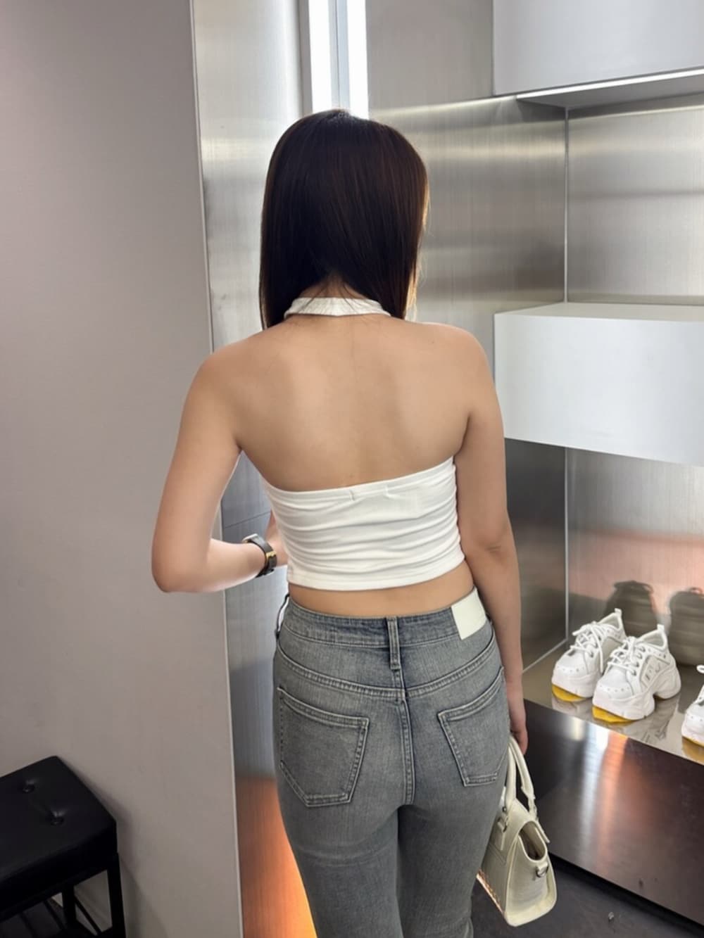 ホワイト系のサンダル、ホワイト系のハンドバッグ、ブルー系のデニムパンツを着用したレディースの夏コーディネートの6枚目の写真