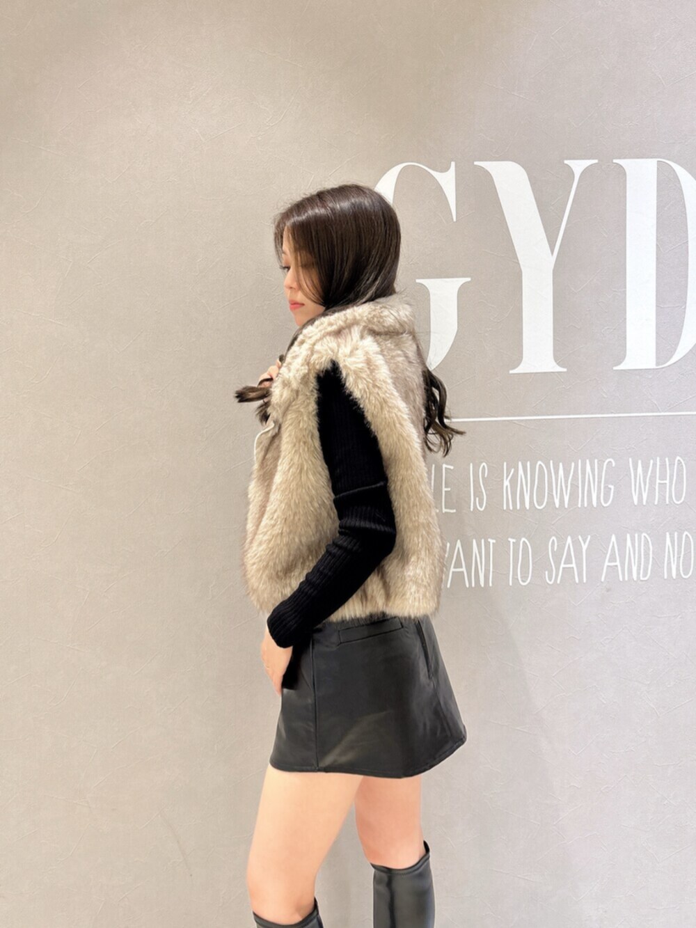 ブラック系のニット/セーター、ブラック系のスカート、ブラック系のブーツを着用したレディースの秋コーディネートの5枚目の写真