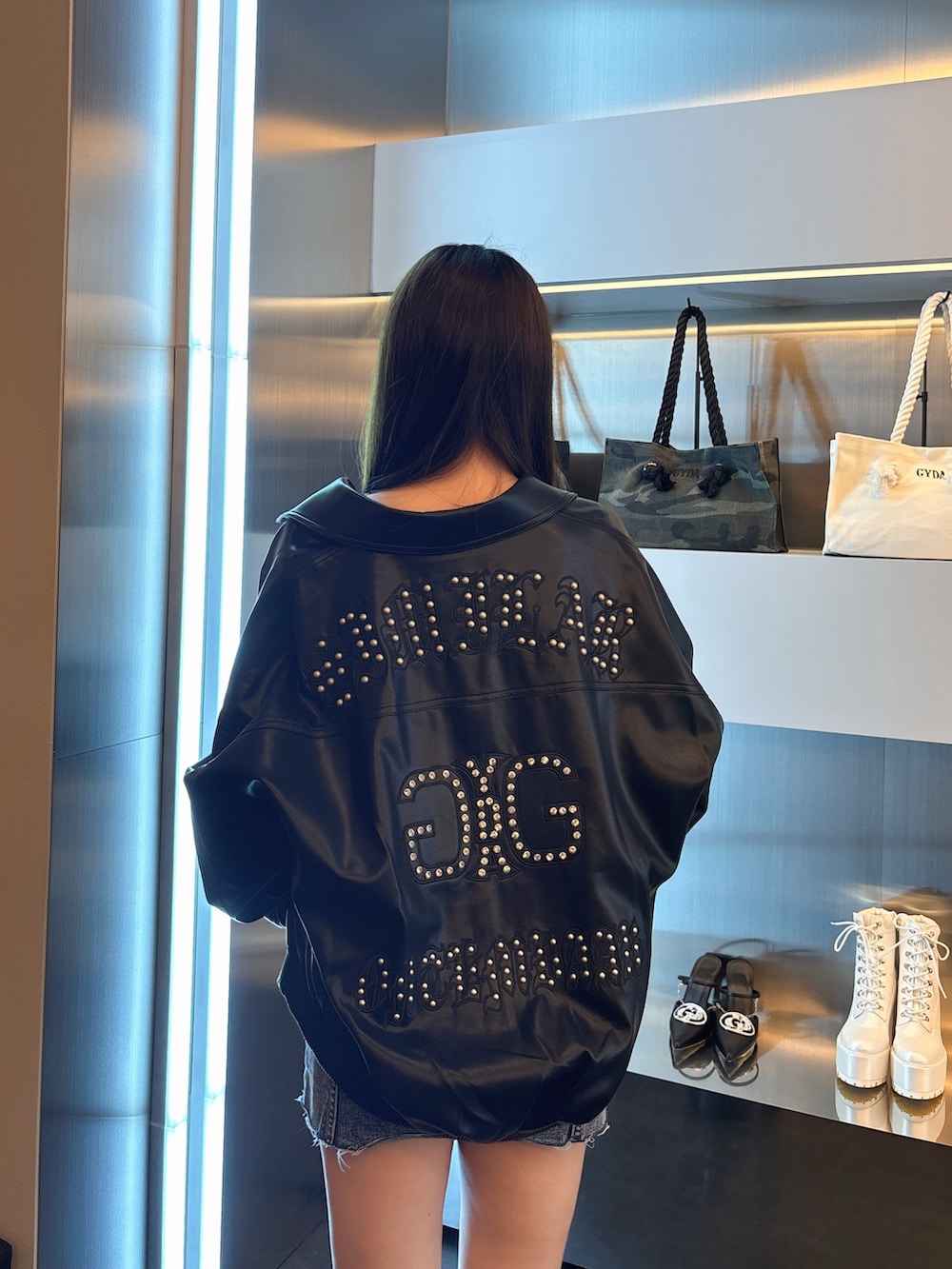 ブルー系のデニムジャケット、ブラック系のブルゾン、ブラック系のブーツを着用したレディースの春コーディネートの6枚目の写真