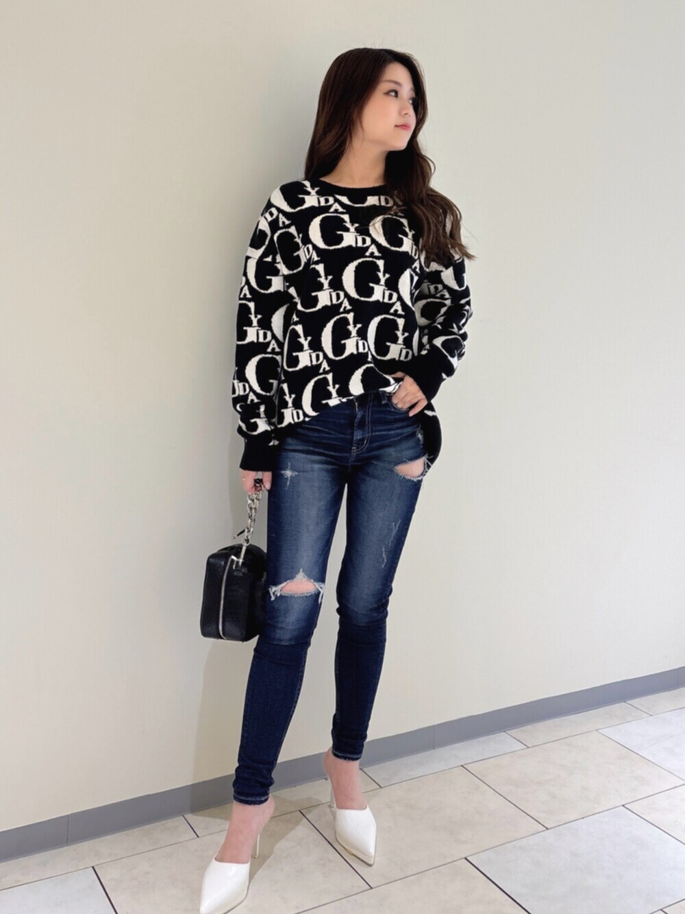 ホワイト系のパンプス、ブラック系のニット/セーター、ブルー系のデニムパンツを着用したレディースの冬コーディネートの2枚目の写真