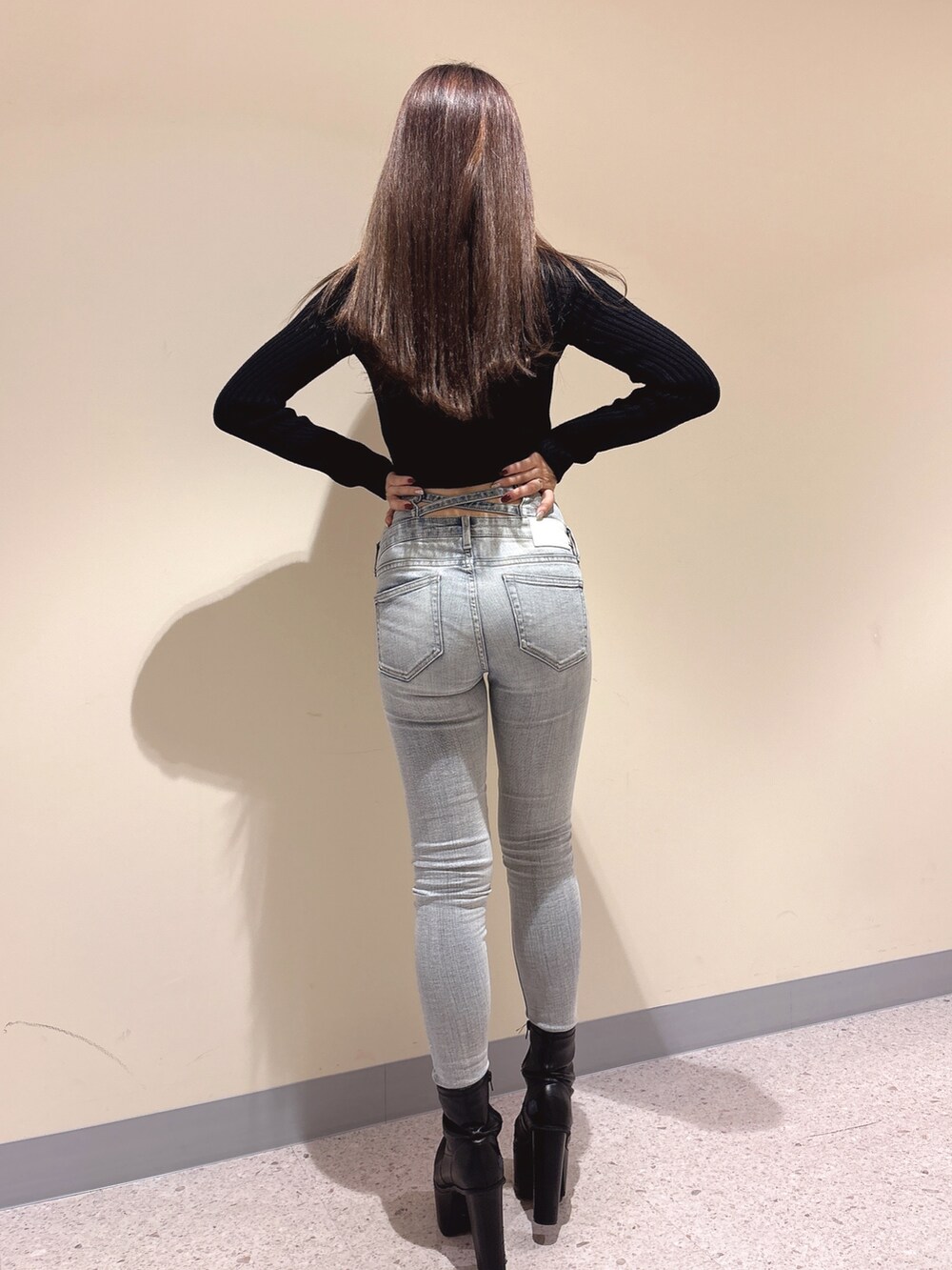 ブラック系のニット/セーター、ブルー系のデニムパンツ、ブラック系のブーツを着用したレディースの秋コーディネートの3枚目の写真