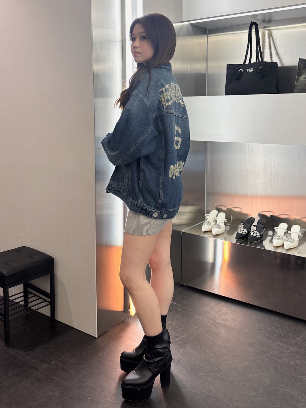 ブラック系のブーツ、シルバー系のワンピース、ブルー系のデニムジャケットを着用したレディースの春コーディネートの2枚目の写真