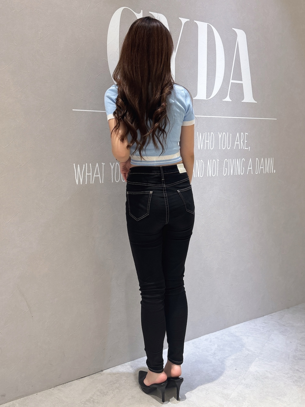 ブルー系のニット/セーター、ブラック系のデニムパンツ、ホワイト系のパンプスを着用したレディースの春コーディネートの3枚目の写真