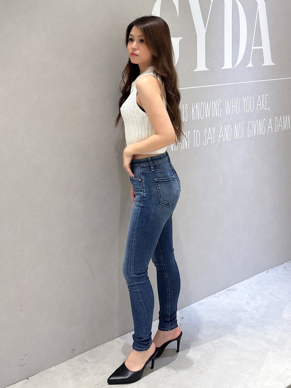 ホワイト系のニット/セーター、ブルー系のデニムパンツ、ホワイト系のパンプスを着用したレディースの夏コーディネートの2枚目の写真