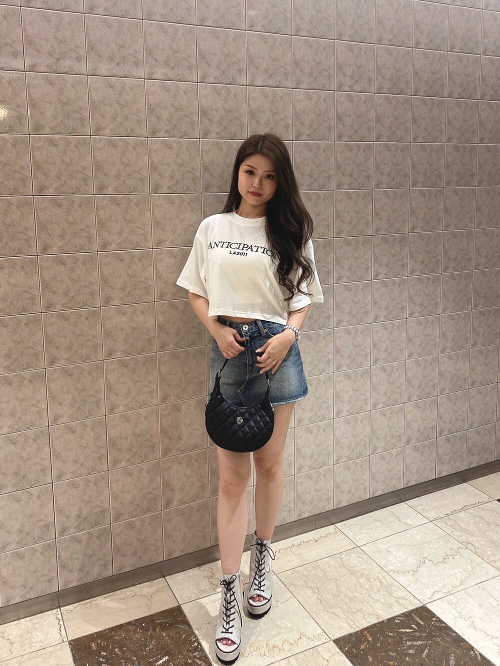 ホワイト系のTシャツ/カットソー、ブルー系のデニムスカート、ホワイト系のブーツを着用したレディースの夏コーディネートの2枚目の写真