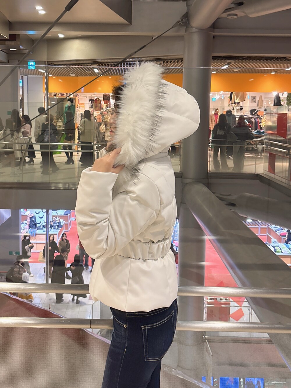 ブラック系のダウンジャケット/コート、ブルー系のデニムパンツ、ブラック系のブーツを着用したレディースの冬コーディネートの5枚目の写真