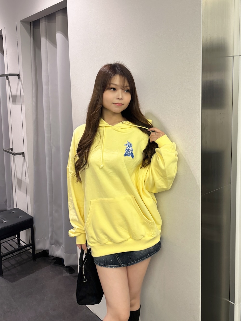 イエロー系のパーカー、ブラック系のハンドバッグ、ブラック系のブーツを着用したレディースの秋コーディネートの4枚目の写真