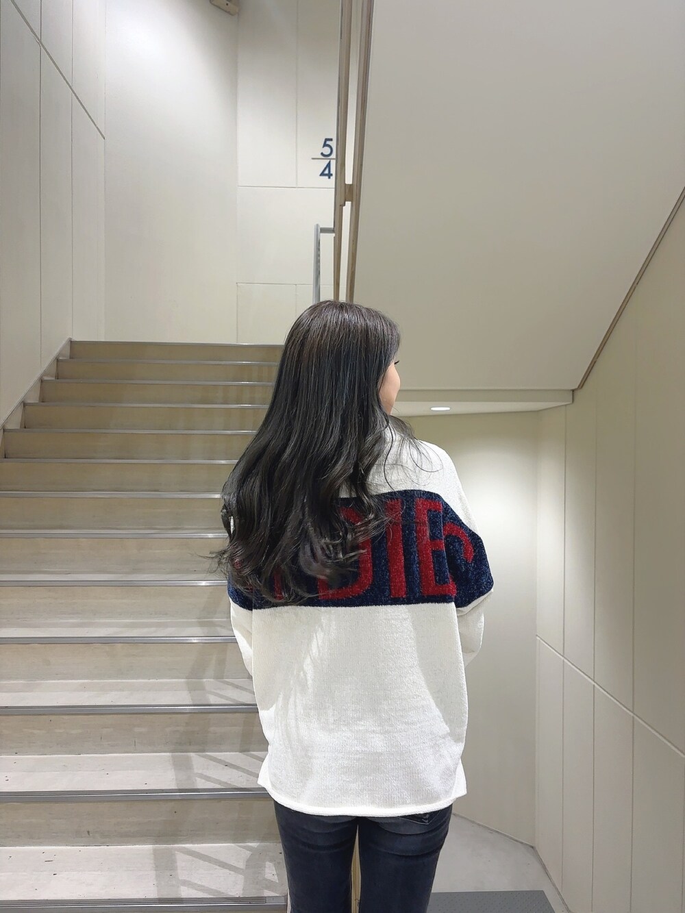 ホワイト系のニット/セーター、ブラック系のデニムパンツ、ブラック系のブーツを着用したレディースの秋コーディネートの5枚目の写真