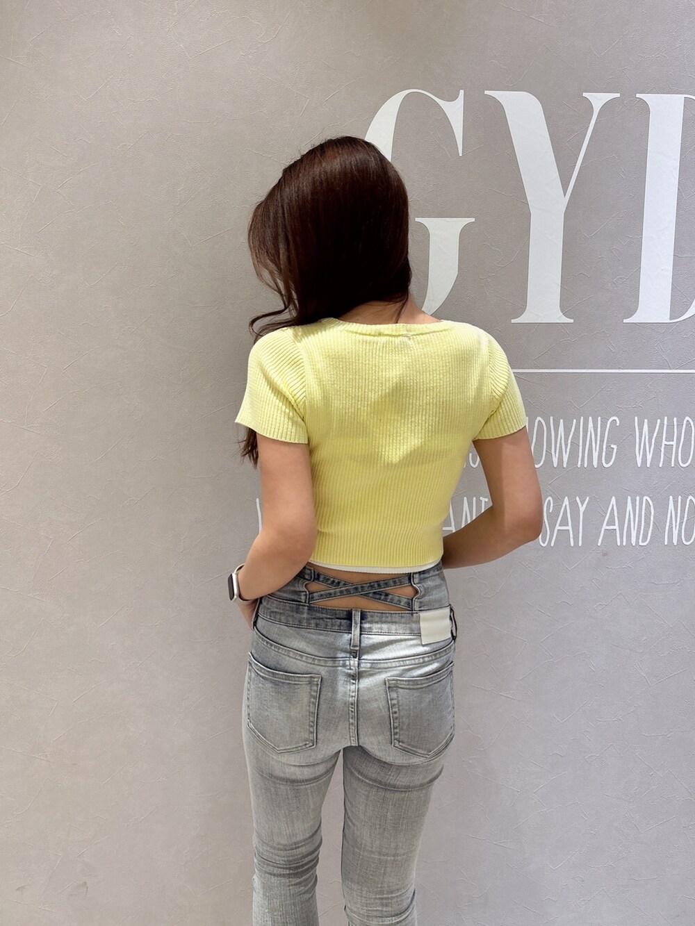 イエロー系のニット/セーター、ブルー系のデニムパンツ、ホワイト系のパンプスを着用したレディースの春コーディネートの6枚目の写真