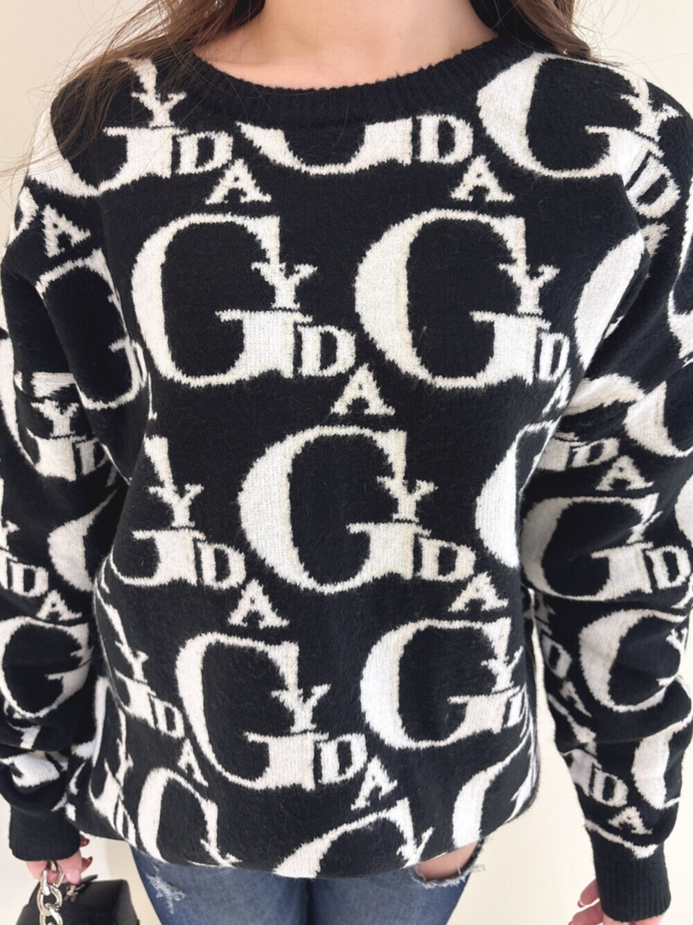 ホワイト系のパンプス、ブラック系のニット/セーター、ブルー系のデニムパンツを着用したレディースの冬コーディネートの9枚目の写真