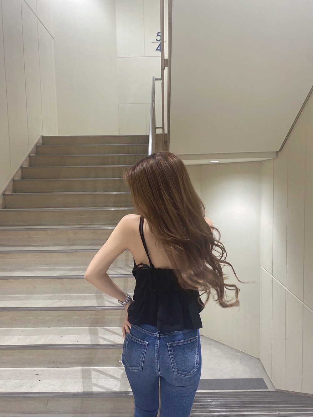 ブラック系のキャミソール、ブルー系のデニムパンツ、ブラック系のパンプスを着用したレディースの夏コーディネートの4枚目の写真
