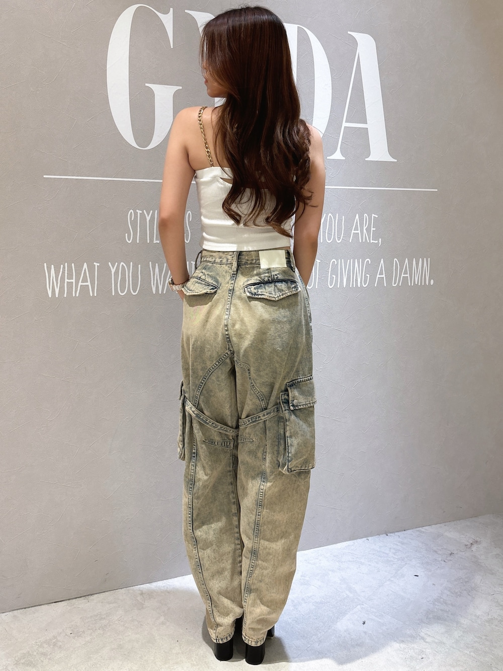 ホワイト系のキャミソール、ブラック系のサンダル、ブルー系のデニムパンツを着用したレディースの夏コーディネートの3枚目の写真