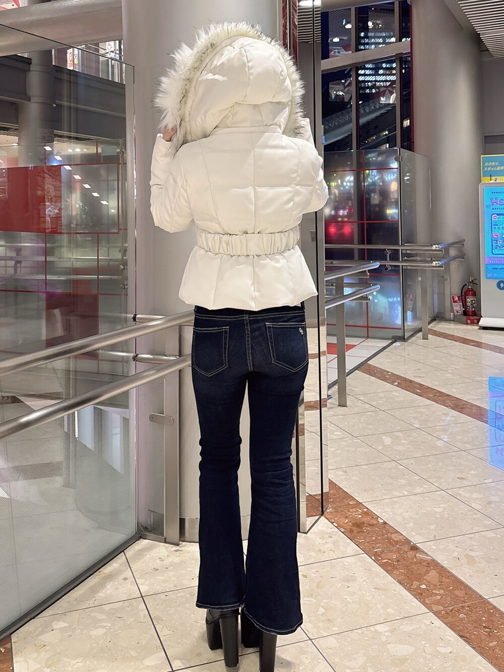 ブラック系のダウンジャケット/コート、ブルー系のデニムパンツ、ブラック系のブーツを着用したレディースの冬コーディネートの3枚目の写真