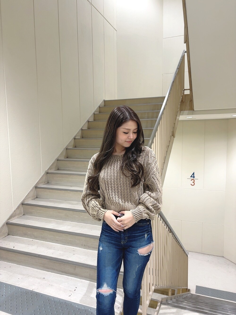 ベージュ系のニット/セーター、ブルー系のデニムパンツ、ホワイト系のパンプスを着用したレディースの冬コーディネートの3枚目の写真