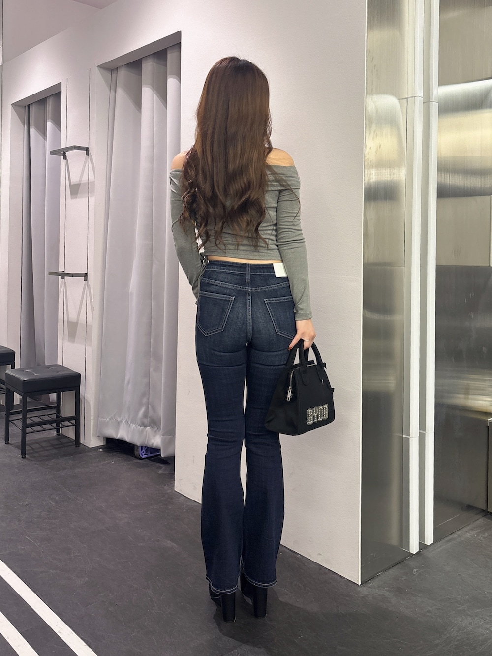 グレー系のTシャツ/カットソー、ブルー系のデニムパンツ、ブラック系のハンドバッグを着用したレディースの秋コーディネートの3枚目の写真
