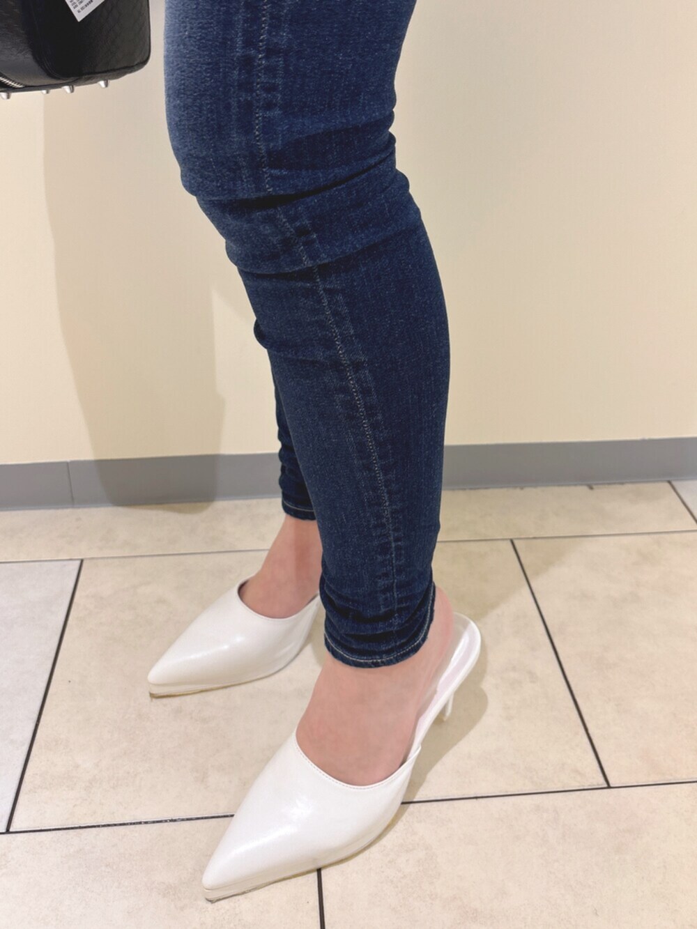 ホワイト系のパンプス、ブルー系のデニムパンツ、ブラック系のショルダーバッグを着用したレディースの冬コーディネートの9枚目の写真