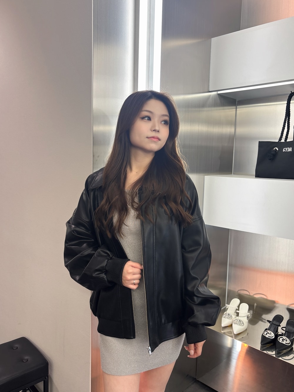 シルバー系のワンピース、ブラック系のブーツ、ブラック系のブルゾンを着用したレディースの春コーディネートの4枚目の写真