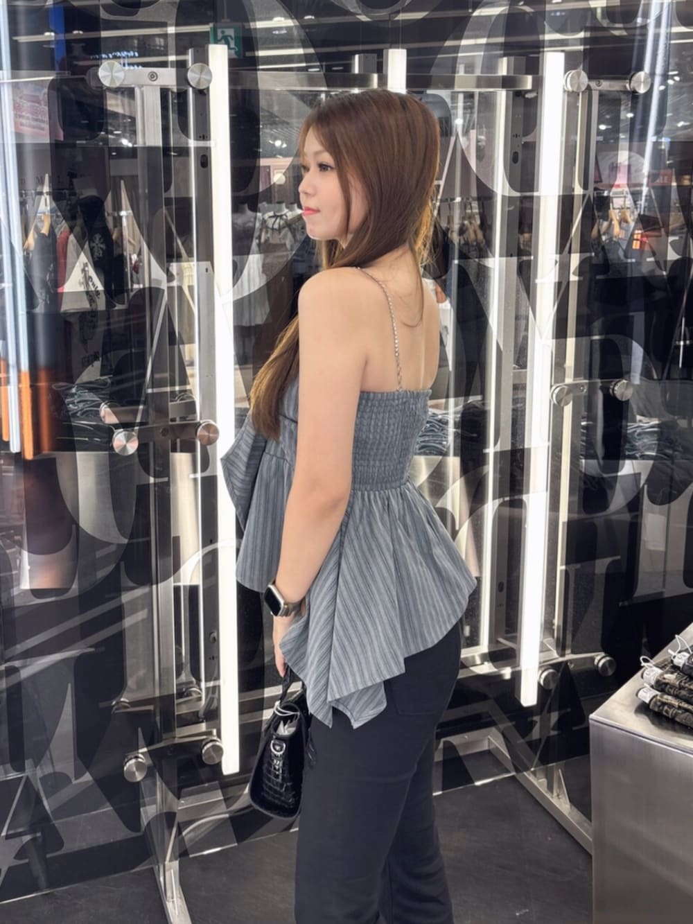 ブルー系のデニムパンツ、ホワイト系のサンダル、ホワイト系のハンドバッグを着用したレディースの夏コーディネートの5枚目の写真