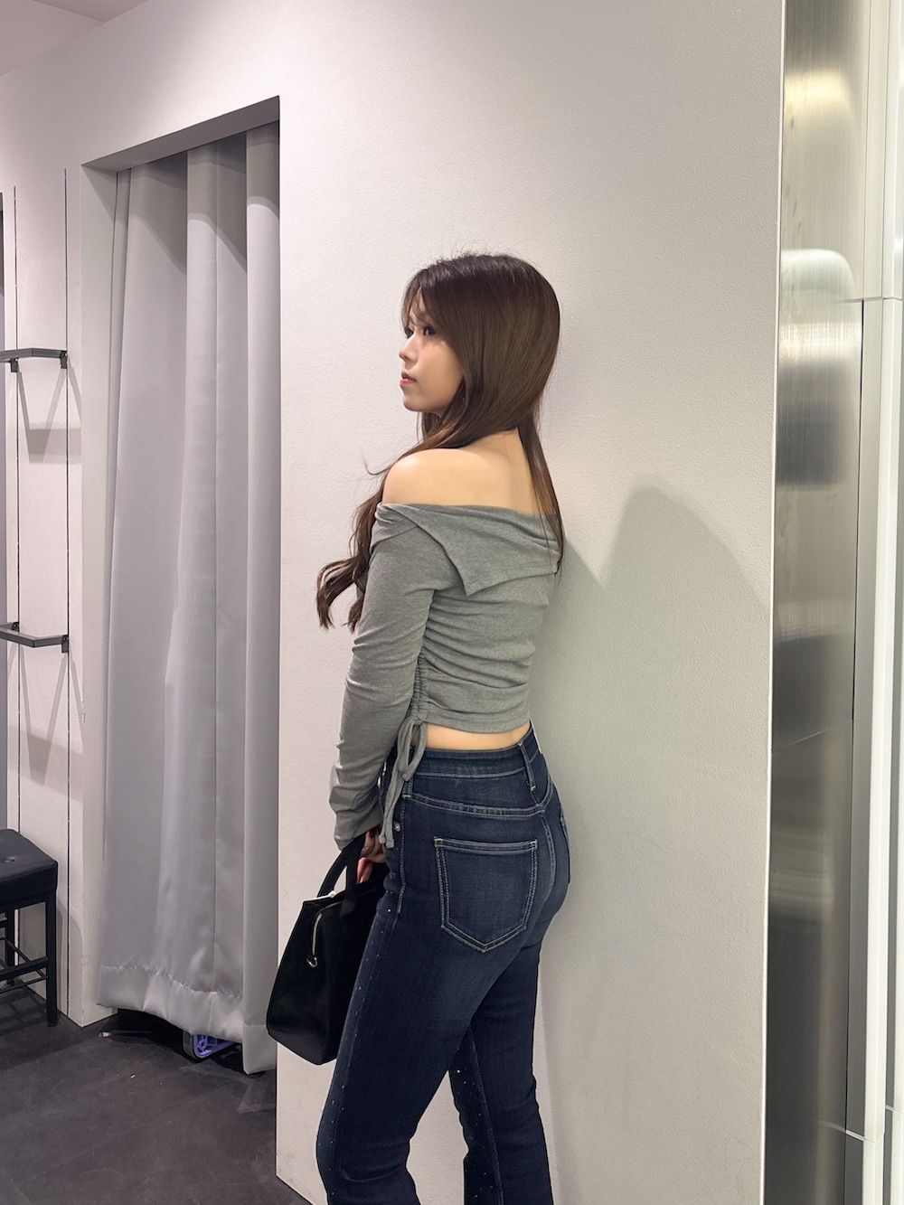 グレー系のTシャツ/カットソー、ブルー系のデニムパンツ、ブラック系のハンドバッグを着用したレディースの秋コーディネートの5枚目の写真