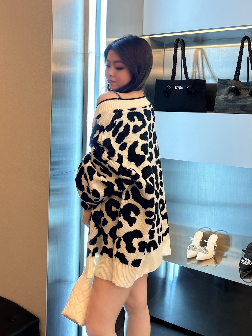 ブルー系のワンピース、ホワイト系のカーディガン/ボレロ、ブラック系のブーツを着用したレディースの春コーディネートの5枚目の写真