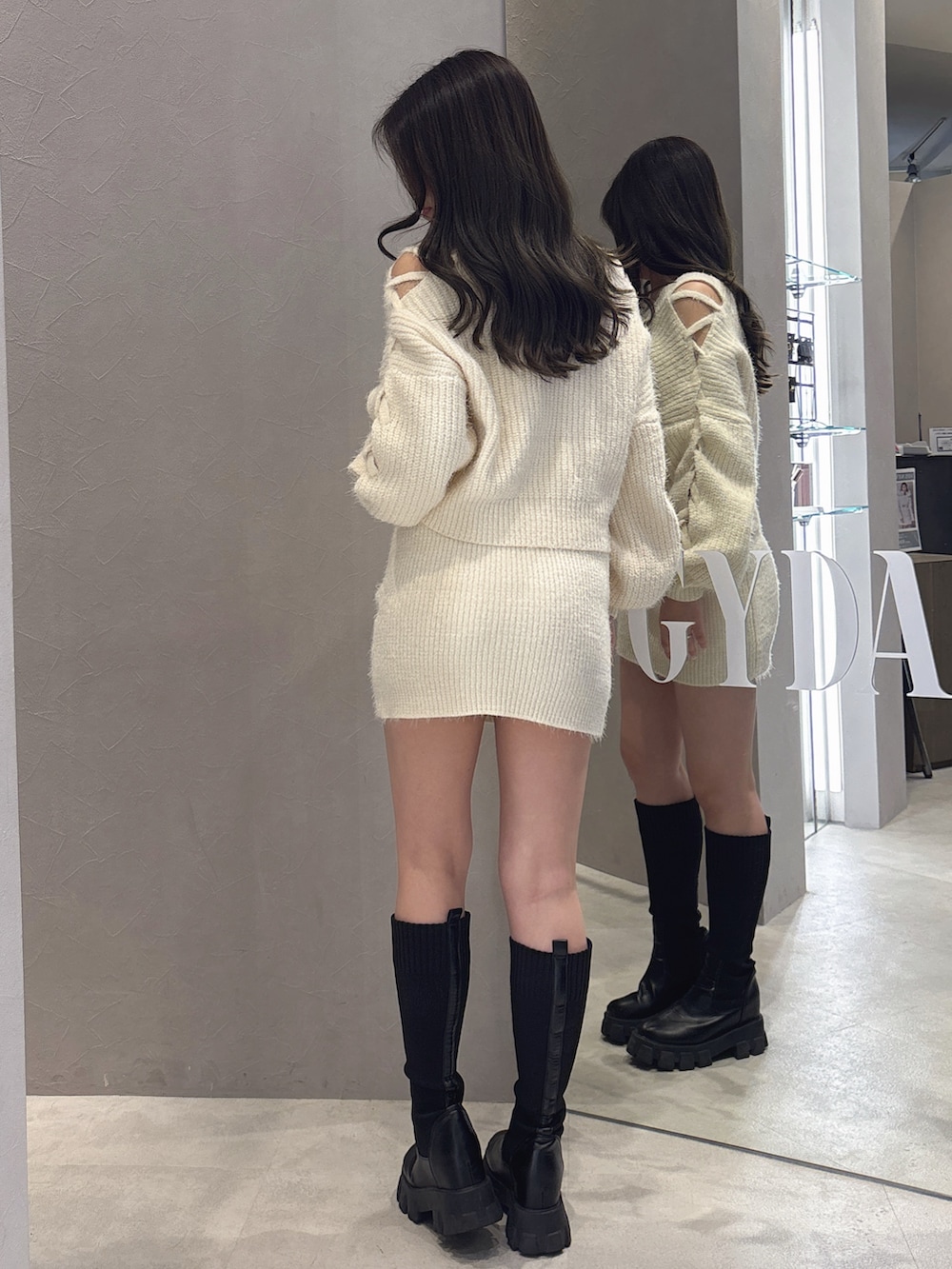 ホワイト系のニット/セーター、ホワイト系のスカート、ブラック系のブーツを着用したレディースの秋コーディネートの3枚目の写真