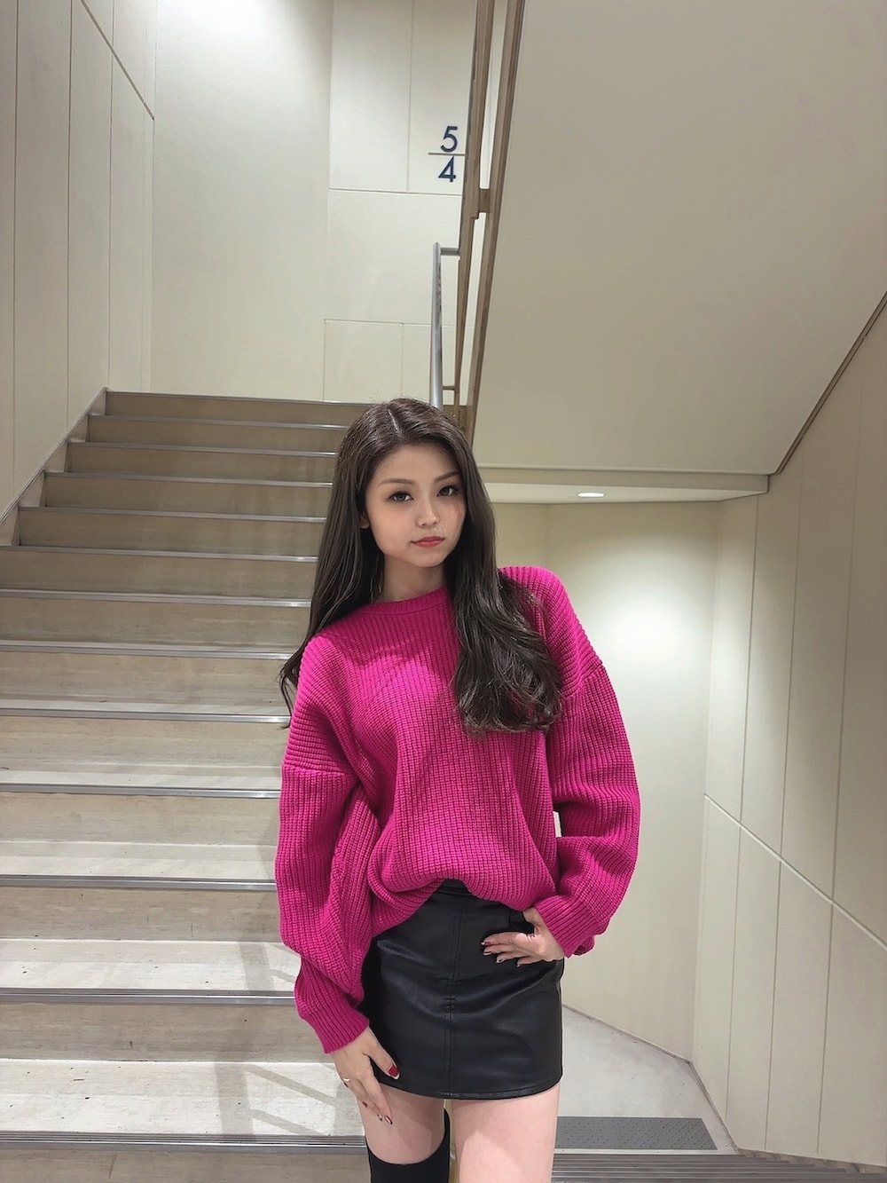 ピンク系のニット/セーター、ブラック系のスカート、ブラック系のブーツを着用したレディースの秋コーディネートの3枚目の写真