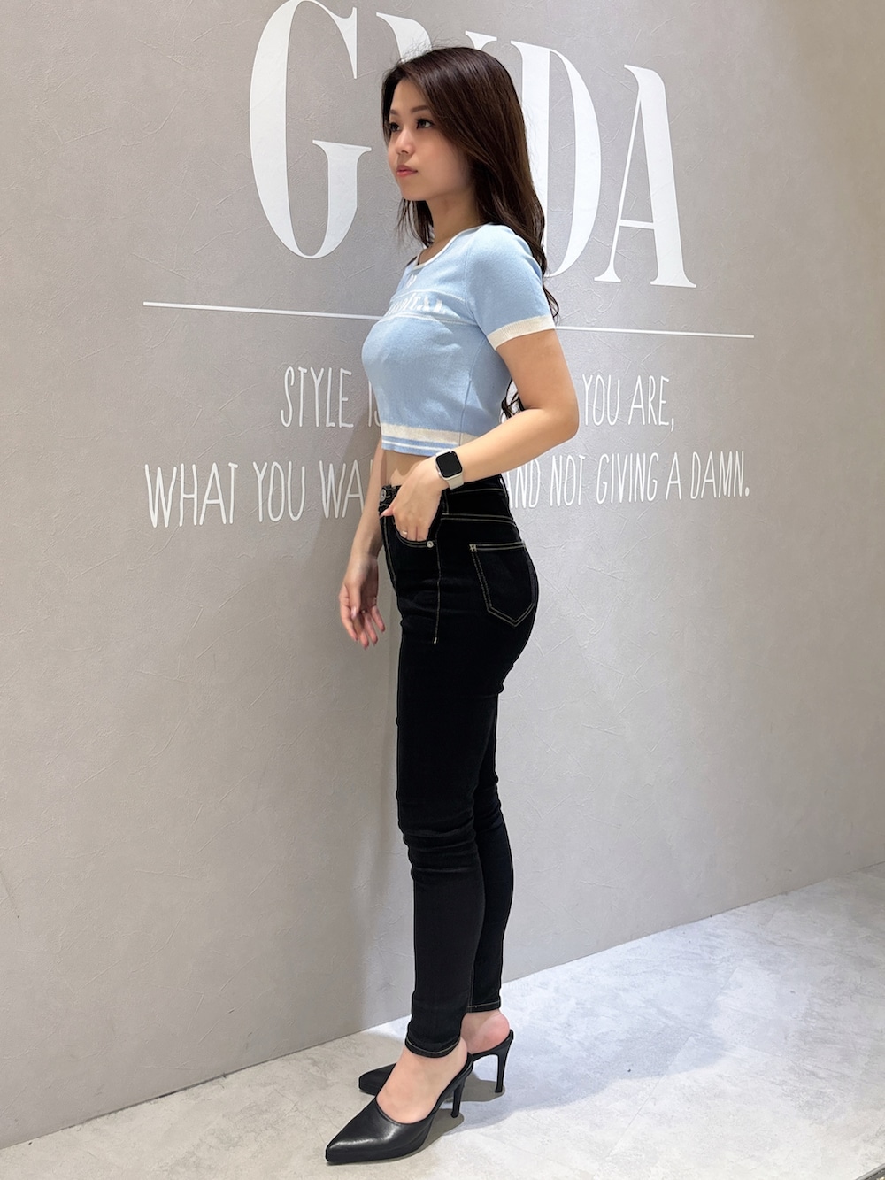 ブルー系のニット/セーター、ブラック系のデニムパンツ、ホワイト系のパンプスを着用したレディースの春コーディネートの2枚目の写真