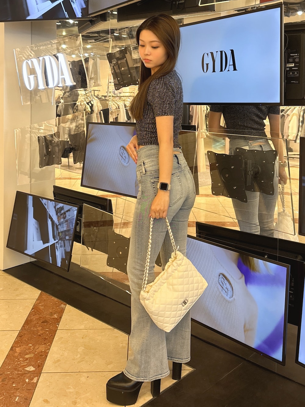 ブラック系のニット/セーター、ブルー系のデニムパンツ、ブラック系のブーツを着用したレディースの春コーディネートの2枚目の写真