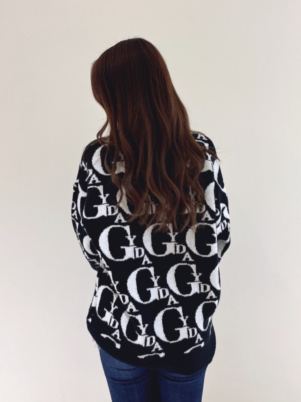 ホワイト系のパンプス、ブラック系のニット/セーター、ブルー系のデニムパンツを着用したレディースの冬コーディネートの8枚目の写真