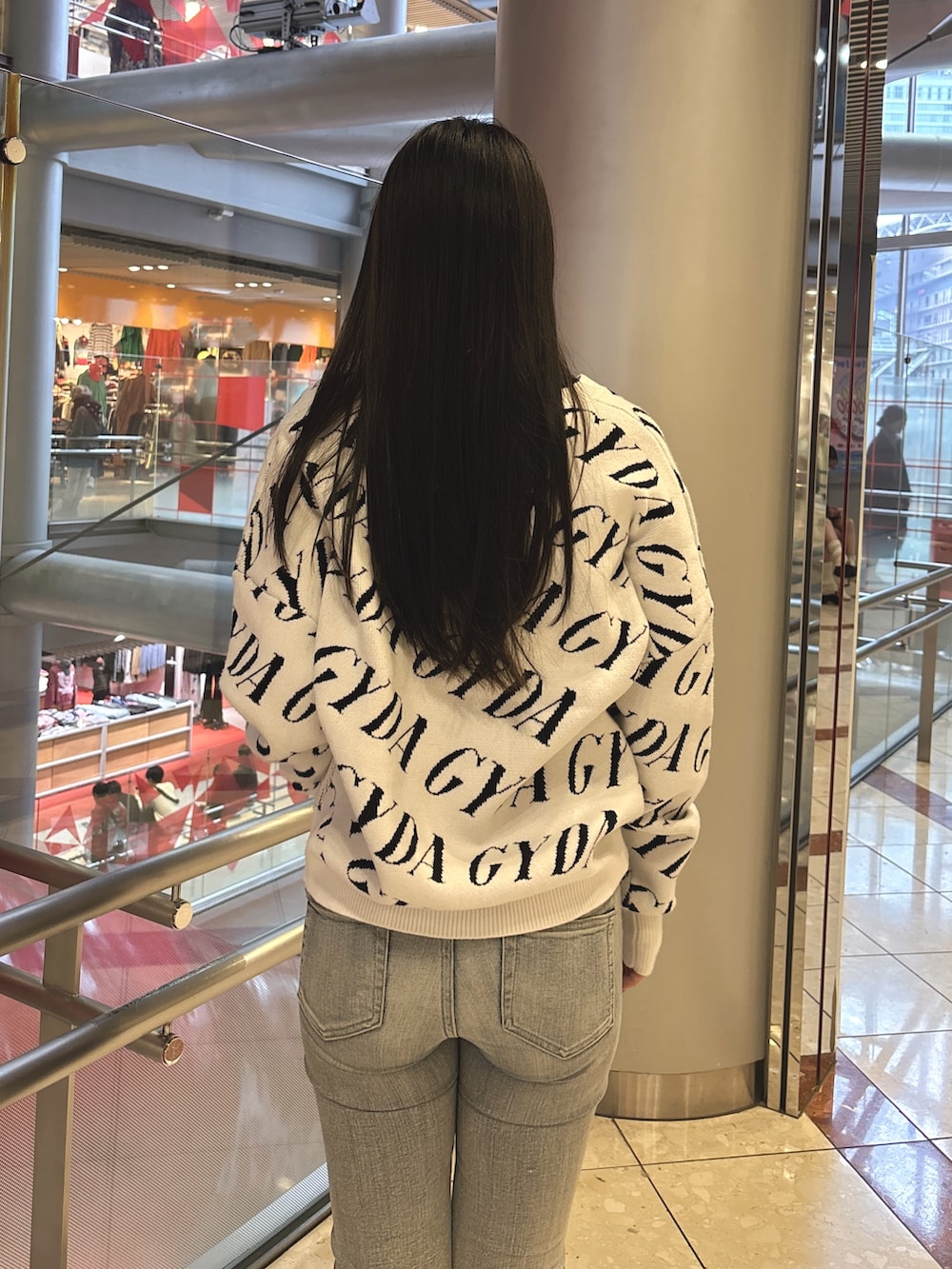 ブラック系のニット/セーター、ブルー系のデニムパンツ、ブラック系のブーツを着用したレディースの春コーディネートの6枚目の写真