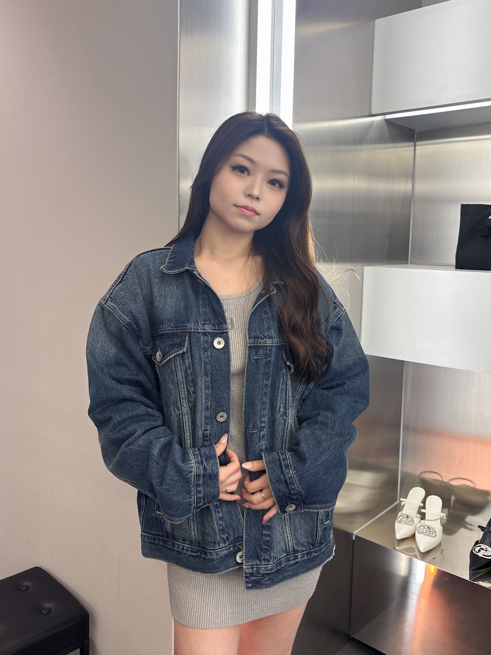 ブラック系のブーツ、シルバー系のワンピース、ブルー系のデニムジャケットを着用したレディースの春コーディネートの4枚目の写真