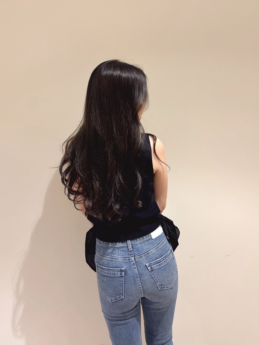 ブラック系のニット/セーター、ブルー系のデニムパンツ、ホワイト系のパンプスを着用したレディースの夏コーディネートの7枚目の写真