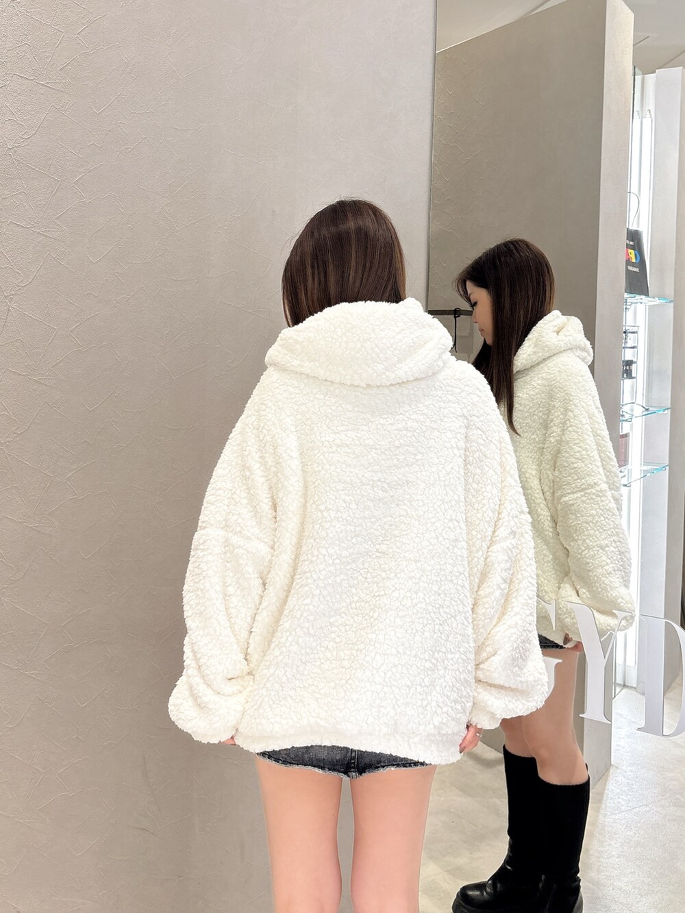 ホワイト系のパーカー、ブルー系のデニムスカート、ブラック系のブーツを着用したレディースの秋コーディネートの6枚目の写真