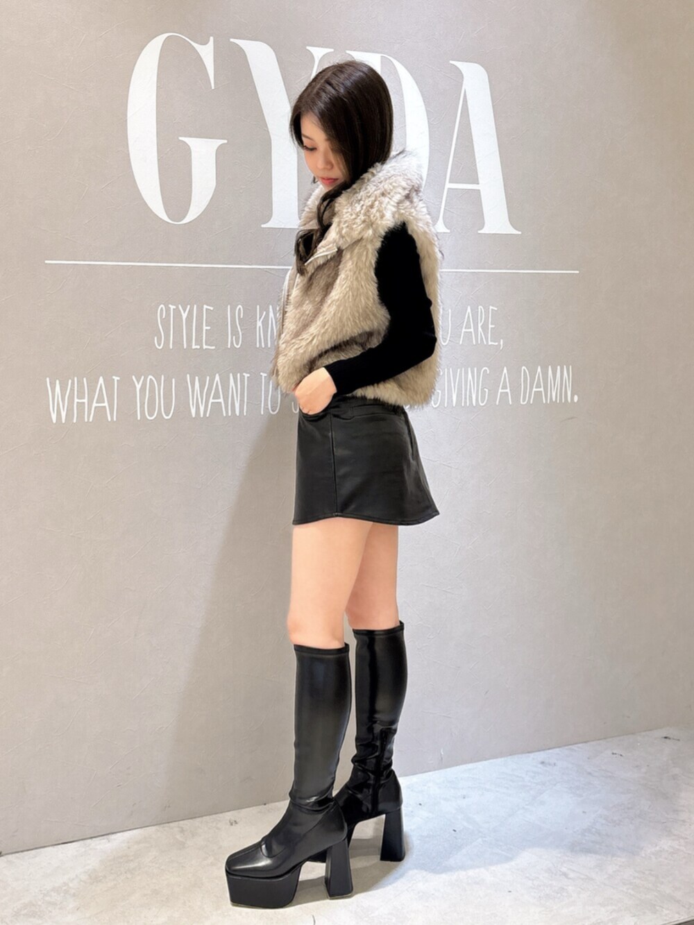 ブラック系のニット/セーター、ブラック系のスカート、ブラック系のブーツを着用したレディースの秋コーディネートの2枚目の写真