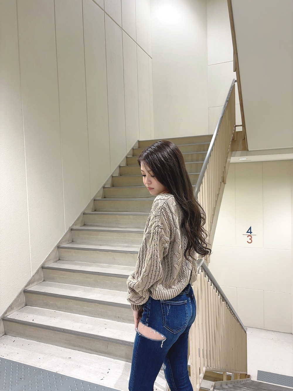 ベージュ系のニット/セーター、ブルー系のデニムパンツ、ホワイト系のパンプスを着用したレディースの冬コーディネートの4枚目の写真